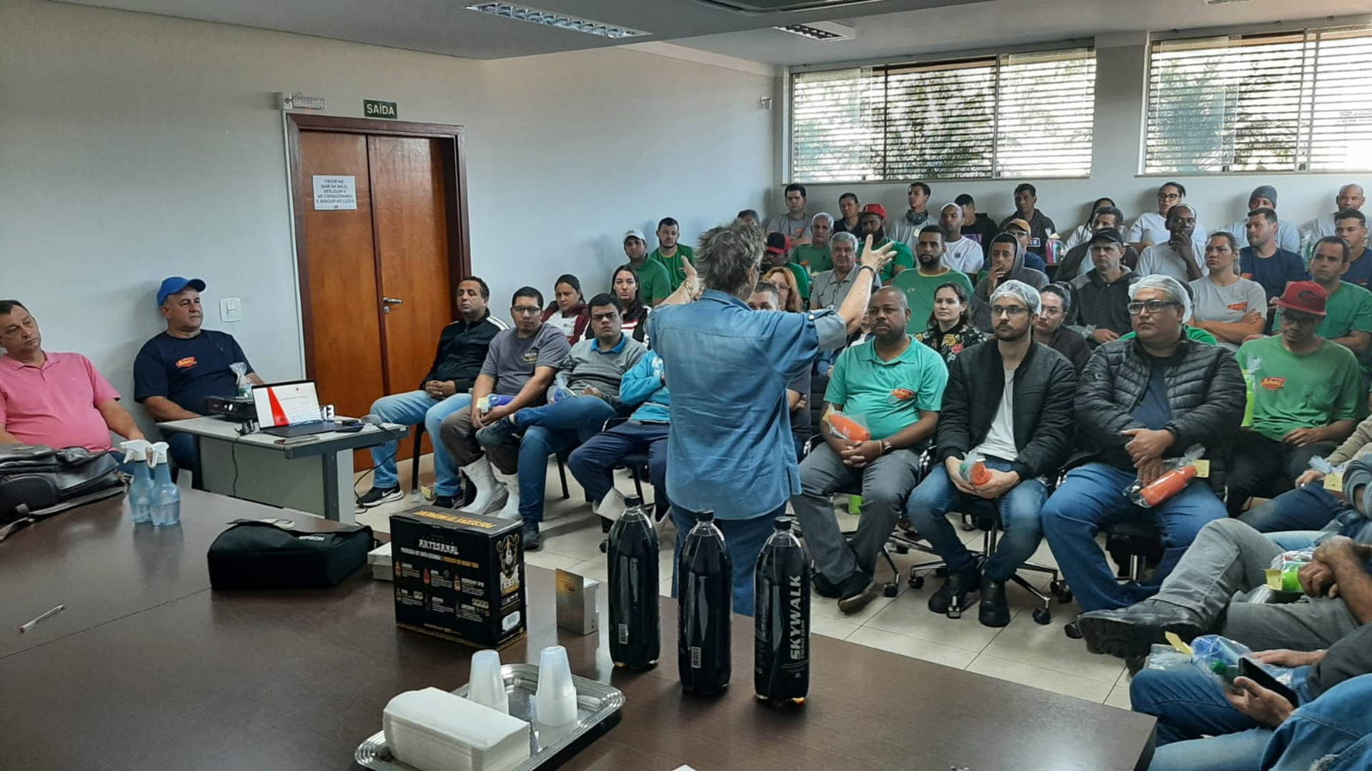 Regina conduzindo treinamento para plateia de colaboradores
